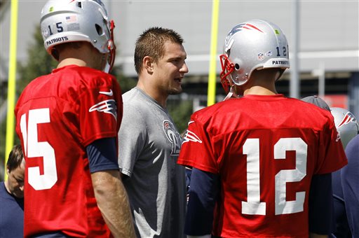 New England Patriots tight end Rob Gronkowski, center, talks with quarterbacks Tom Brady (12) and Ryan Mallett (15) during the Patriots' joint workout with the Tampa Bay Buccaneers at NFL football training camp, in Foxborough, Mass., Thursday, Aug. 15, 2013. (AP Photo/Stew Milne)