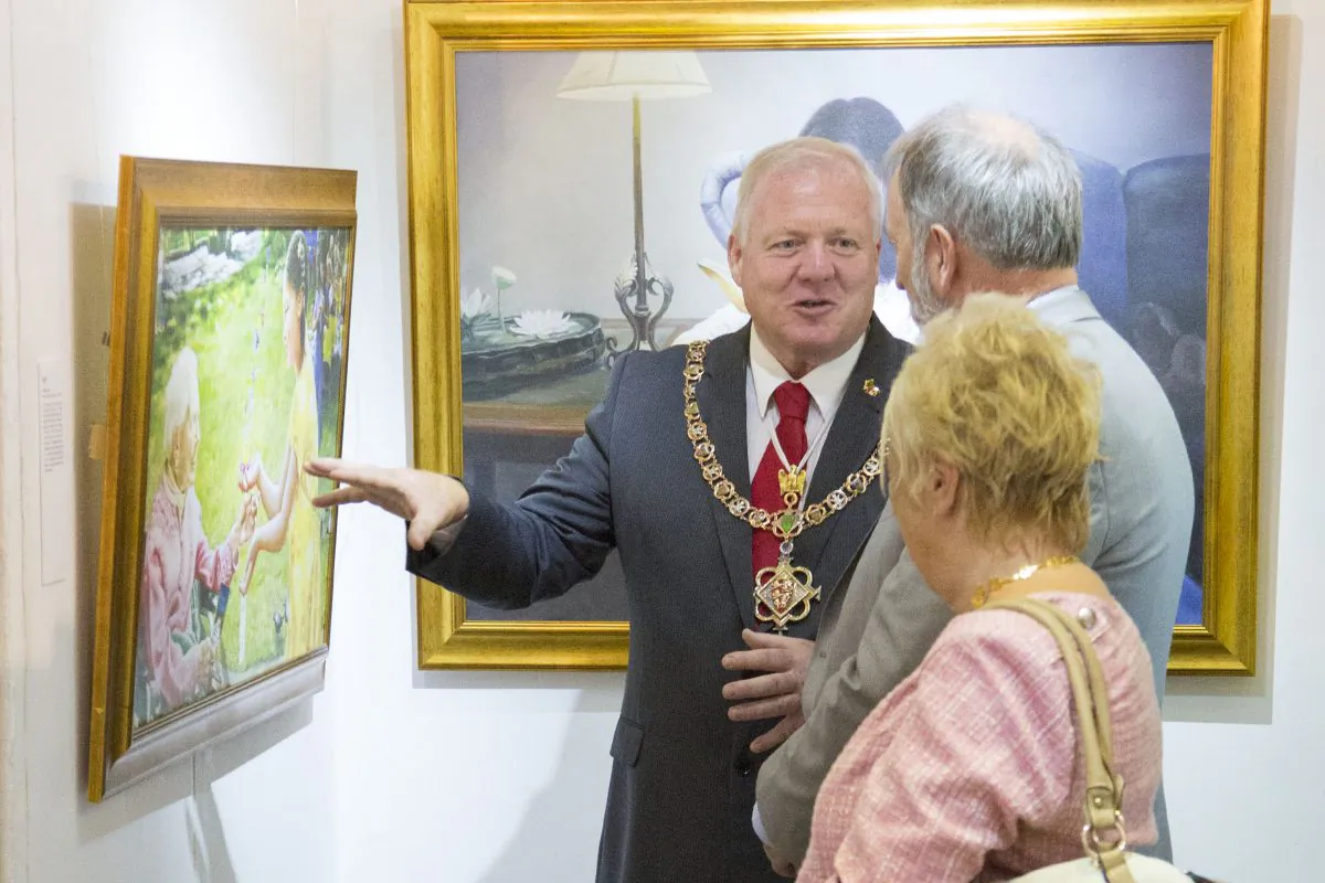 The Mayor of Caernarfon Roy Owen talks to Eddie Aitken, Director of Zhen Shan Ren Arts (UK), in front of the painting 'The Gift' by Kathleen Gillis. (Simon Gross/Epoch Times)