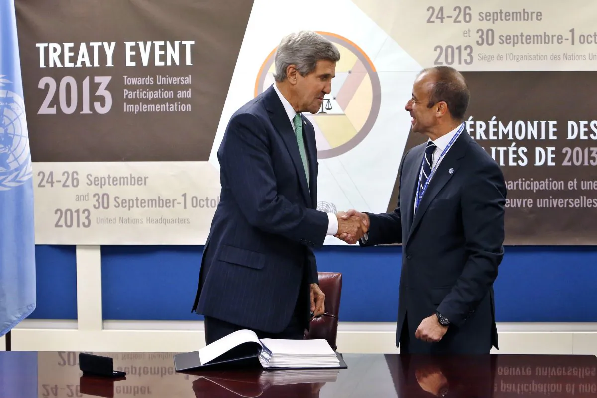 U.S. Secretary of State John Kerry shakes hands with Under Secretary-General for Legal Affairs Miguel Serpa Soares after signing the Arms Trade Treaty at U.N. headquarters on Sept. 25, 2013. The Harper government is drawing criticism for its continued refusal to sign the landmark treaty. (AP Photo/Jason DeCrow)