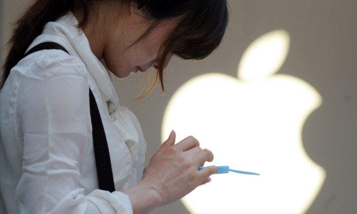 A woman uses her mobile phone outside an Apple store in Shanghai on May 7, 2012. Apple reportedly reached an agreement to sell iPhones through China Mobile, the nation's biggest wireless provider. (Peter Parks/AFP/Getty Images)