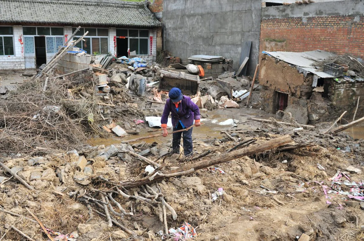 A woman cleans up debris at a destroyed home after flood waters receded on Sept. 17, 2013 in Minxian, China, in Gansu Province. On July 22, the same area was struck by an earthquake. (ChinaFotoPress/Getty Images)