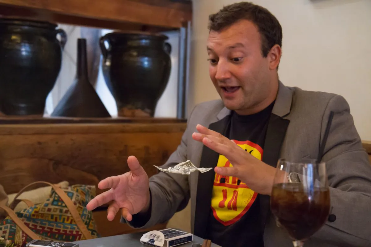 Josh Beckerman, the foodie magician, performs a magic trick by making a dollar bill levitate at Il Buco Alimentari and Vineria restaurant in New York City. (Benjamin Chasteen/Epoch Times) 