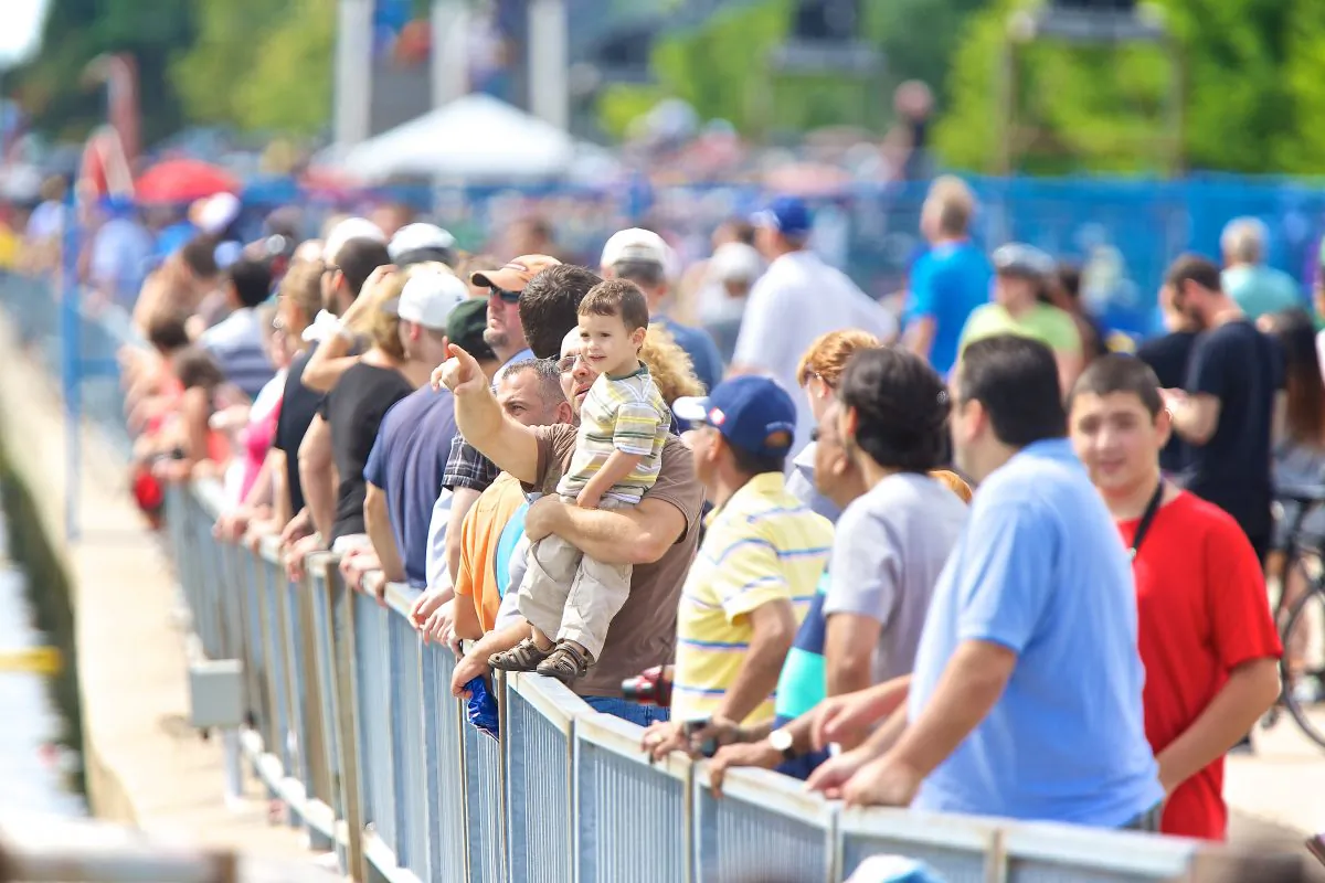 As crowds line the Lakeshore boardwalk, a father directs his sons' attention towards the sky as an aerialist approaches. (Quincy Clark/DQC Photo)