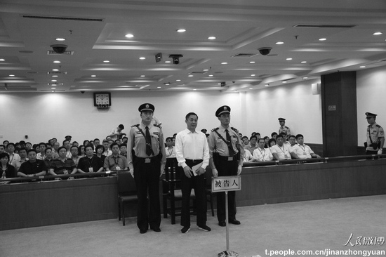 Bo Xilai stands between two officers at the court in Jinan, the capital of Shandong Province, on Sunday. He was sentenced to life in prison. (Weibo.com)
