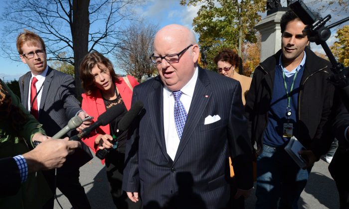 Sen. Mike Duffy is questioned by media as he arrives at the Senate on Parliament Hill in Ottawa on Tuesday, Oct. 22, 2013. In the House of Commons on Oct 23, Prime Minister Stephen Harper accused Duffy of playing the victim card because he was ordered to repay inappropriate expenses. (The Canadian Press/Sean Kilpatrick)