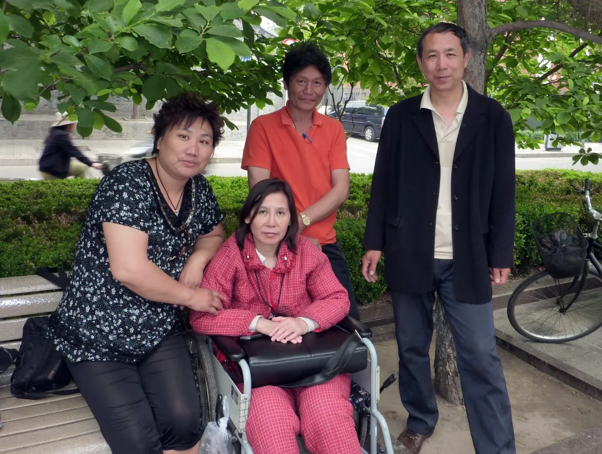 Ni Yulan (C) and her husband, Dong Jiqin (2nd R), pose with a supporter during an interview at the Imperial City Heritage Park in Beijing, May 27, 2010. Ni was released on Oct. 3 after serving a two-and-a-half-year sentence for her human rights activism. (Robert J. Saiget/AFP/Getty Images)