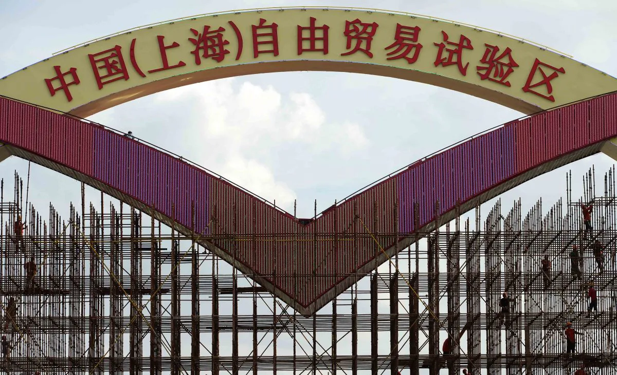 This picture taken on Sept. 23, 2013 shows laborers working on a large sign reading 'China (Shanghai) Pilot Free Trade Zone' on a gate of Shanghai Waigaoqiao Free Trade Zone (FTZ), before its formal launch in September 29. The free convertibility of the yuan inside the FTZ may trigger a wave of corruption and rent seeking by Chinese regime officials, argues Frank Xie. (STR/AFP/Getty Images) 