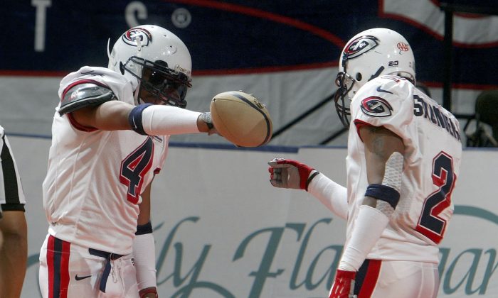 B.J. Barre #4 of the Columbus Destroyers celebrates his touchdown against the New York Dragons by pretending to pour a drink for teammate David Saunders #2 during their Arena Football game on March 3, 2006 at the Nassau Coliseum in Uniondale, New York.  (Jim McIsaac/Getty Images)