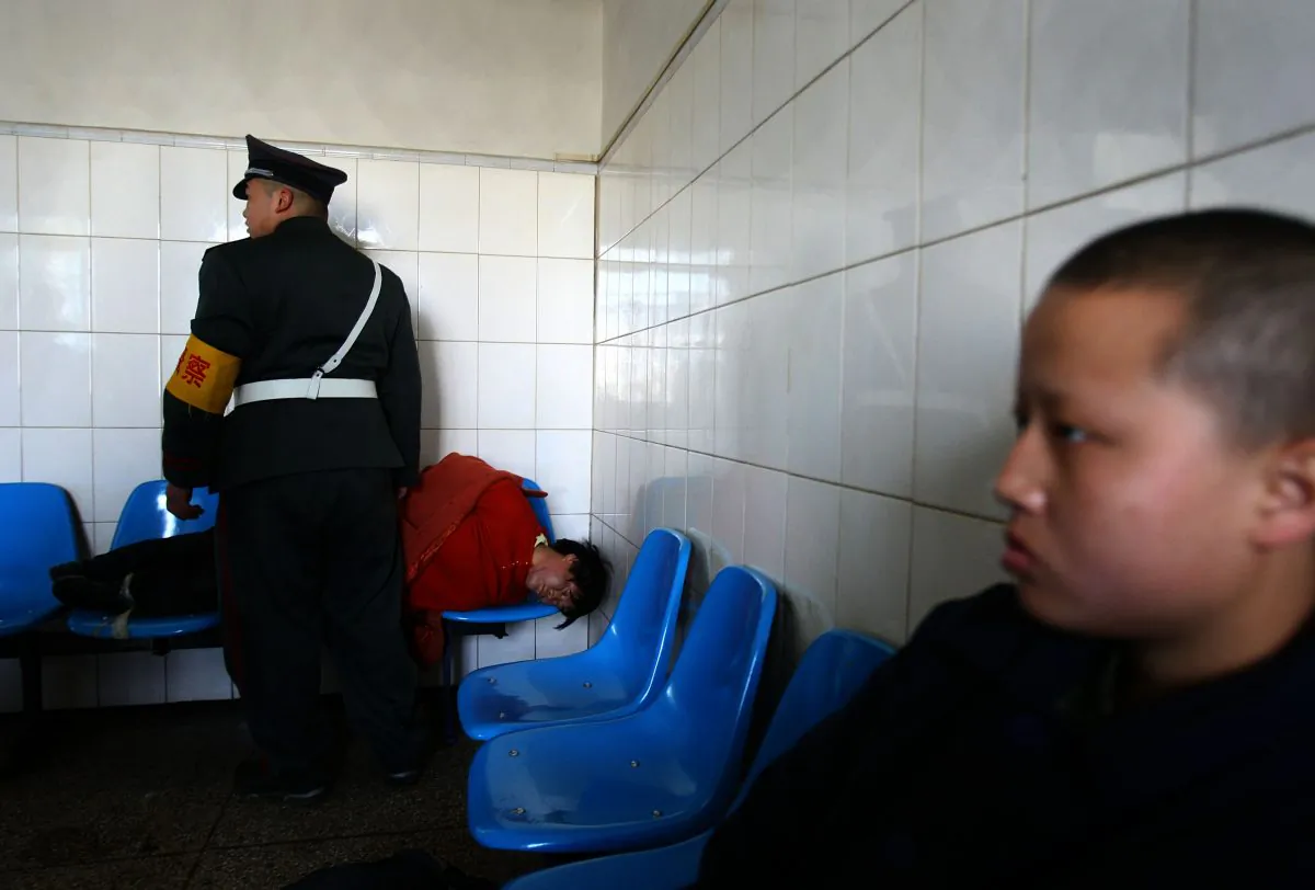 A man who was just escorted to the Kunming Mental Hospital lies on chairs, in Kunming, Yunnan Province, China, on Dec. 1, 2007. (China Photos/Getty Images)