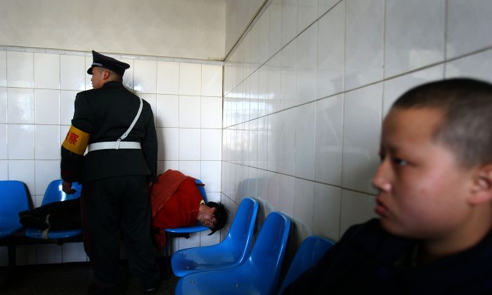 A man who was just escorted to the Kunming Mental Hospital lies on chairs, in Kunming, Yunnan Province, China, on Dec. 1, 2007. (China Photos/Getty Images)