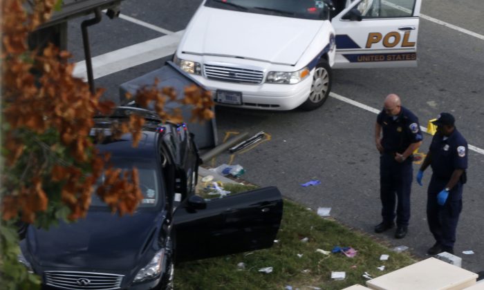 The black car driven by the suspect--identified as Miriam Carey--in the Washington D.C. car chase on Thursday, with Capitol Hill police officers nearby. Carey has been identified by law enforcement sources as the woman who was driving the car and was fatally shot by police. (AP Photo/Charles Dharapak)