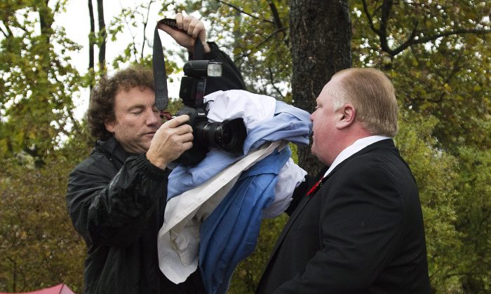 Toronto Mayor Rob Ford, right, pushes a member of the media off his property as he leaves his home in Toronto on Thursday, Oct. 31, 2013. A judge on Wednesday ordered the release of police documents in the drug case against a friend of Ford. Peter Jacobsen, a lawyer for various Canadian news organizations that pushed to release the records, said the case against Alexander Lisi involves the mayor. (AP Photo/, Nathan Denette)