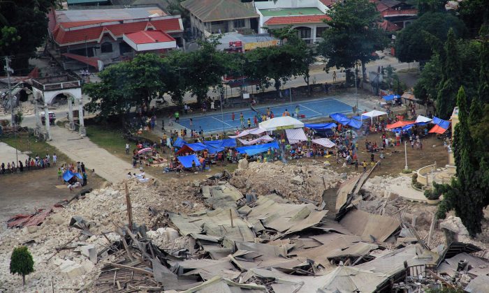Residents living in tents beside the rubbles of the Our Lady of Light Catholic church after a powerful earthquake struck Loon town, Bohol province, central Philippines Wednesday Oct. 16, 2013. The 7.2-magnitude earthquake that struck the central Philippines and killed more than a hundred people also dealt a serious blow to the region's historical and religious legacy by heavily damaging a dozen or more churches, some of them hundreds of years old. (AP Photo/ Philippine Air Force)