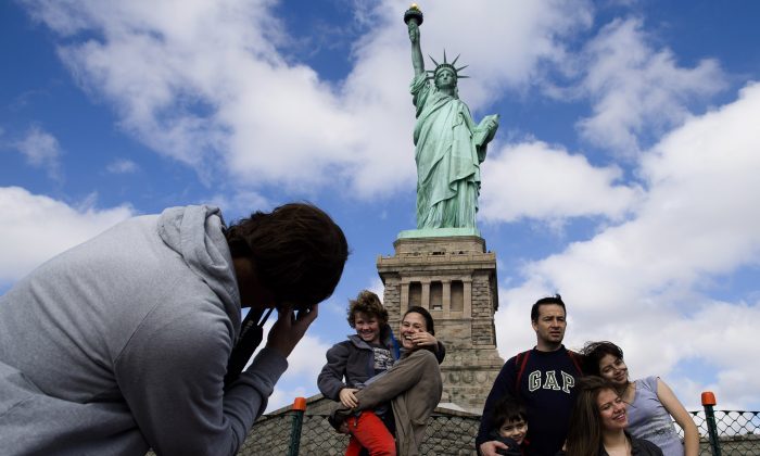 Tourists pose for photographs in front of the Statue of Liberty in New York Harbor, Oct. 13. 2013. (John Minchillo/AP)