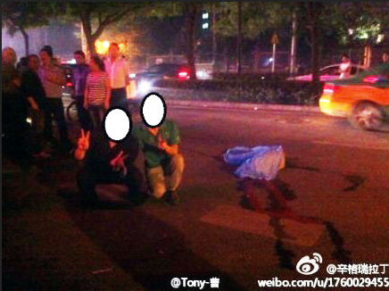 Two Chinese men posed next to the body of a car crash victim in Shaanxi Province. One was tracked down by a reporter, and claimed not to remember the incident because they were drunk at the time. (Weibo.com)