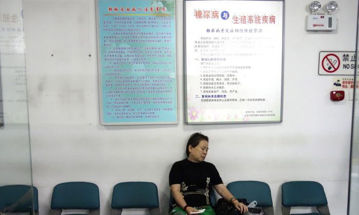 A woman waits to receive treatment as she sits in front of a billboard showing how to avoid diabetes at a diabetes hospital in Beijing on Sep. 4, 2013. Almost 12 percent of adults in China had diabetes in 2010, a slightly higher proportion than in the United States. (Wang Zhao/AFP/Getty Images)