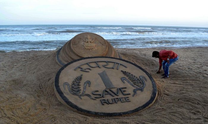 Indian sand artist Sudarsan Pattnaik puts the finishing touches to his sand sculpture of a rupee coin in front of a Hindu Goddess on the beach at Puri, some 65km from Bhubaneswar on August 22, 2013. The rupee, which has hit record low against the U.S. dollar has not deterred those with dreams to go abroad as the returns on investment have also increased manifold times. (Strdel/AFP/Getty Images)
