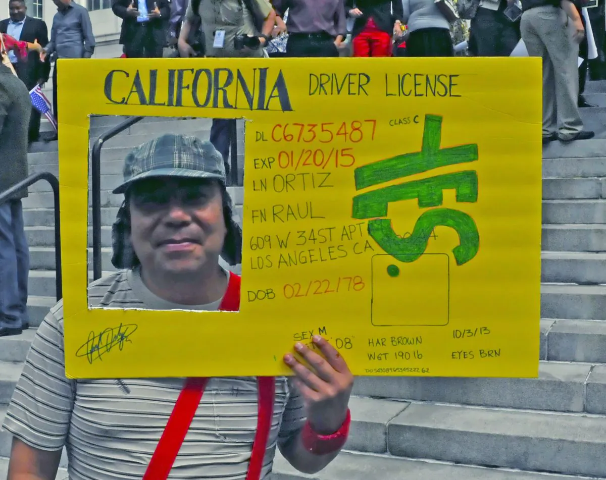 Raul Ortiz (alias) danced on the steps for joy, celebrating the passage of AB-60 with other undocumented immigrants while holding his “soon to be license” with his live photo, in Los Angeles, Calif., Oct. 3. (Robin Kemker/The Epoch Times)