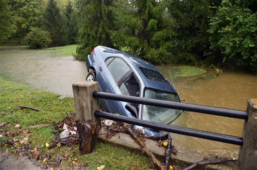 A car is upended in a creek in the 3300 Blk. of Ten Broeck Way, in Louisville, Ky.,, appearing to have driven off the roadway during flooding conditions on Sunday, Oct. 6, 2013. Dozens of people in homes hit by flooding of low-lying areas around Louisville and Jefferson County had to be evacuated overnight, some by rescue personnel using boats, authorities said Sunday. (AP Photo/The Courier-Journal, Scott Utterback)