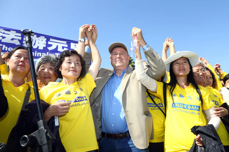 Congressman Dana Rohrabacher holds hands with Falun Gong practitioners during a rally calling for an end to the persecution to Falun Gong in China, at Long Beach in Los Angeles on Oct. 20. (Song Xianglong/Epoch Times)