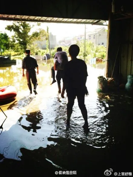 A 60-year-old villager in Zhejiang Province carried a communist official wearing leather shoes to prevent them getting wet, while visiting an area severely affected by flooding after Typhoon Fitow. (Weibo.com)