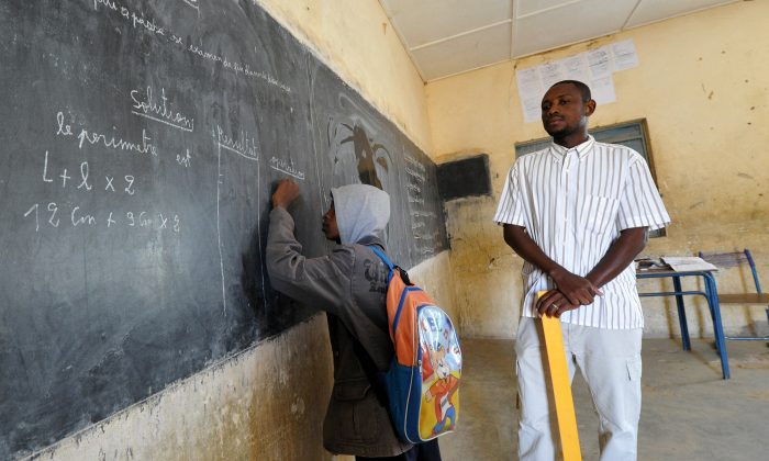 A student writes at the blackboard as the teacher looks on in a classroom in Gao, in the north of Mali, on the first day of the reopening of schools after the French bombing of Islamist targets, on Feb. 4, 2013. (Sia Kambou/AFP/Getty Images)