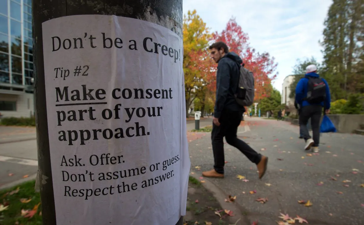 University of British Columbia students walk past a sexual assault poster on campus on October 30, 2013. The RCMP is investigating six sex assaults that occurred at UBC since April. (The Canadian Press/Darryl Dyck)