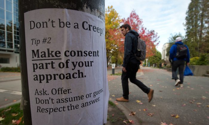 University of British Columbia students walk past a sexual assault poster on campus on October 30, 2013. The RCMP is investigating six sex assaults that occurred at UBC since April. (The Canadian Press/Darryl Dyck)