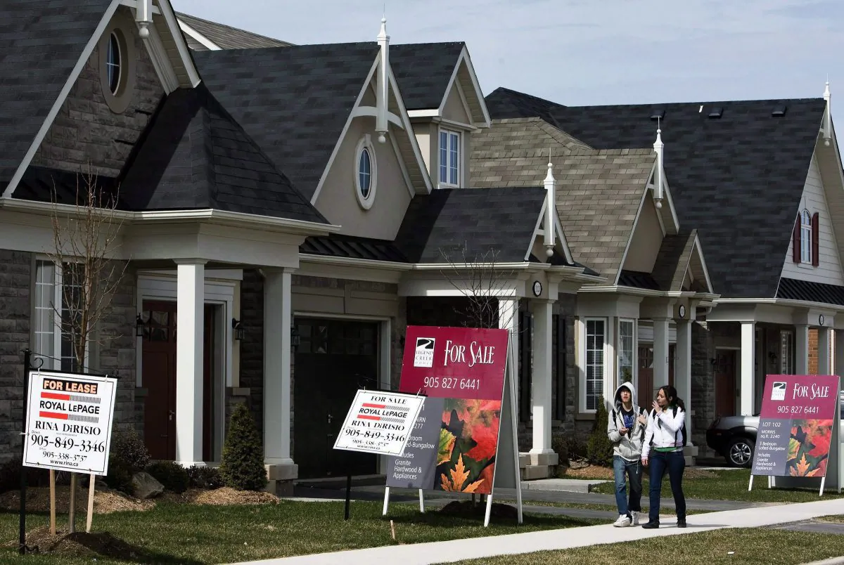 People walk past homes for sale in Oakville, Ont., in this file photo. (The Canadian Press/Nathan Denette)