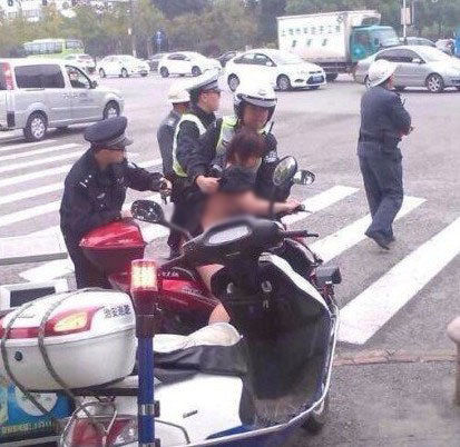 Screenshot showing a woman in Shanghai who took off her clothes after police fined her for driving in the wrong direction. (Hug China/Screenshot/Epoch Times)