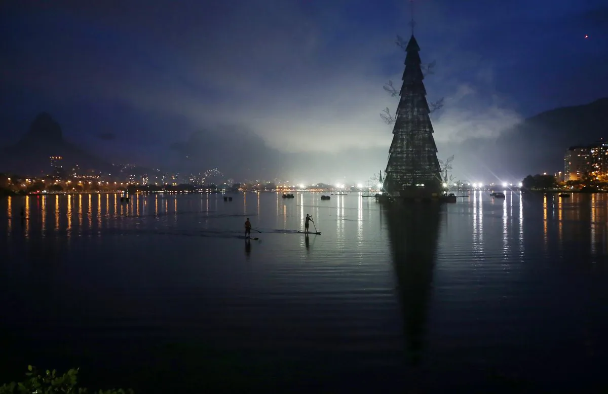 DEC 1: Stand-up paddle boarders row past before the lighting ceremony for Rio de Janeiro's famed floating Christmas tree in Lagoa Rodrigo de Freitas on November 30, 2013 in Rio de Janeiro, Brazil. The constructed tree is the largest floating Christmas tree in the world according to the Guinness Book of World Records. The tree is 85 meters tall and is displayed by three million microlights. (Mario Tama/Getty Images)