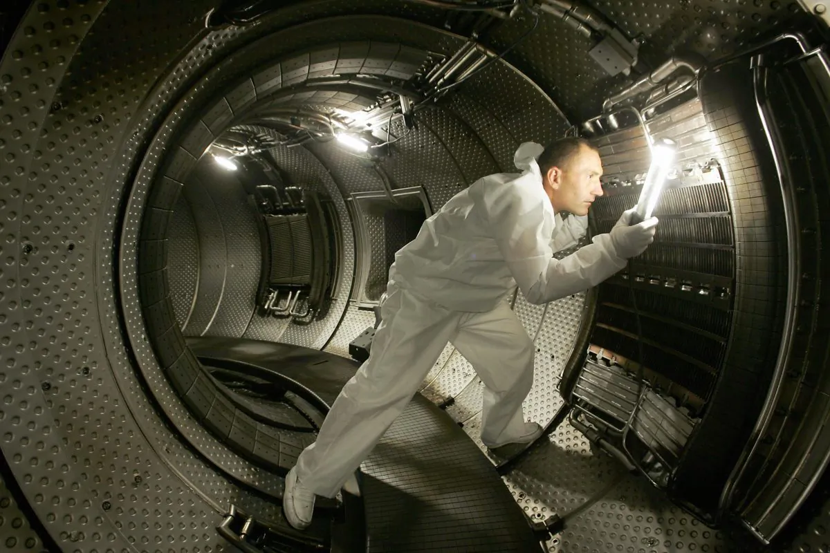 A technician checks a plasma heating system inside a chamber of a nuclear reactor in this file photo. Typical fusion experiments involve a tokamak reactor, but the National Ignition Facility's method of using powerful lasers has successfully produced clean nuclear energy. (Boris Horvat/AFP/Getty Images)
