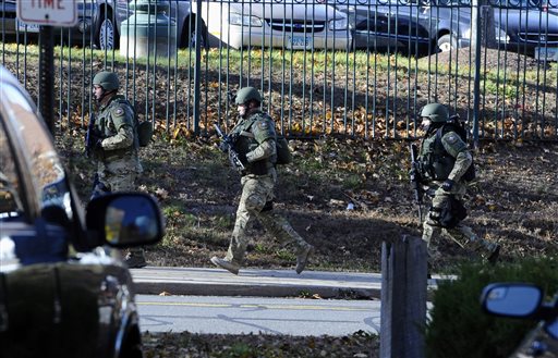SWAT run in a line on the campus of Central Connecticut State University, Monday, Nov. 4, 2013, in New Britain, Conn. An armed man was spotted on the campus of Central Connecticut State University, prompting a schoolwide lockdown and warnings for students to stay away from windows as police SWAT teams swarmed the area. University spokesman Mark McLaughlin said, "Somebody was seen either with a gun or was thought to have a gun." (AP Photo/Jessica Hill)