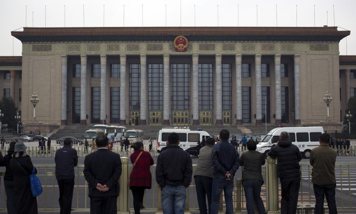 People watch as police officers check visitors in front of the Great Hall of the People during a gathering of the 205-member Central Committee's third annual plenum in Beijing, China Saturday, Nov. 9, 2013. The watchword for the Chinese Communist Party’s Third Plenum of the 18th Central Committee has been “reform.” (AP Photo/Andy Wong)