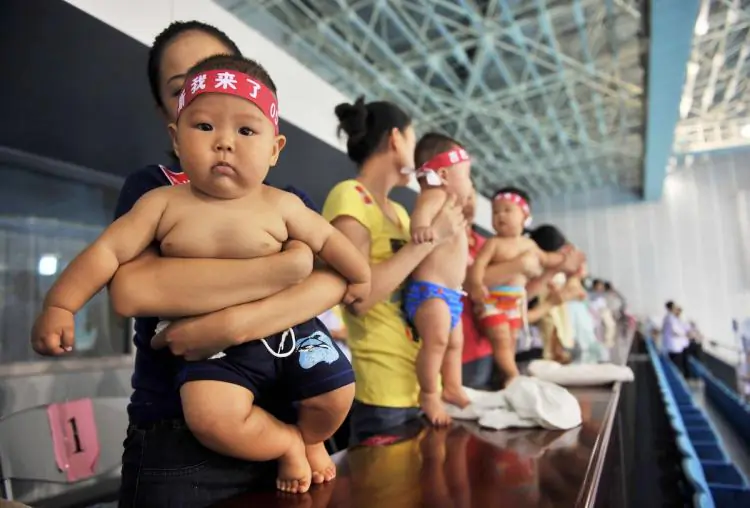 Increasing numbers of wealthy Chinese couples are hiring the services of American surrogate mothers to give birth to their babies to circumvent China's one child policy. In the photo, hundreds of Chinese babies accompanied by their parents prepare to take part in a baby swimming contest. (STR/Getty Images) 