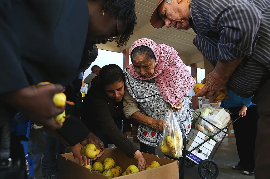 People pick through a box of pears as they wait in line at a food bank on November 1, 2013. An estimated 47 million Americans will see their food stamp benefits cut starting this month, and deeper cuts to the program are expected soon. (Justin Sullivan/Getty Images)