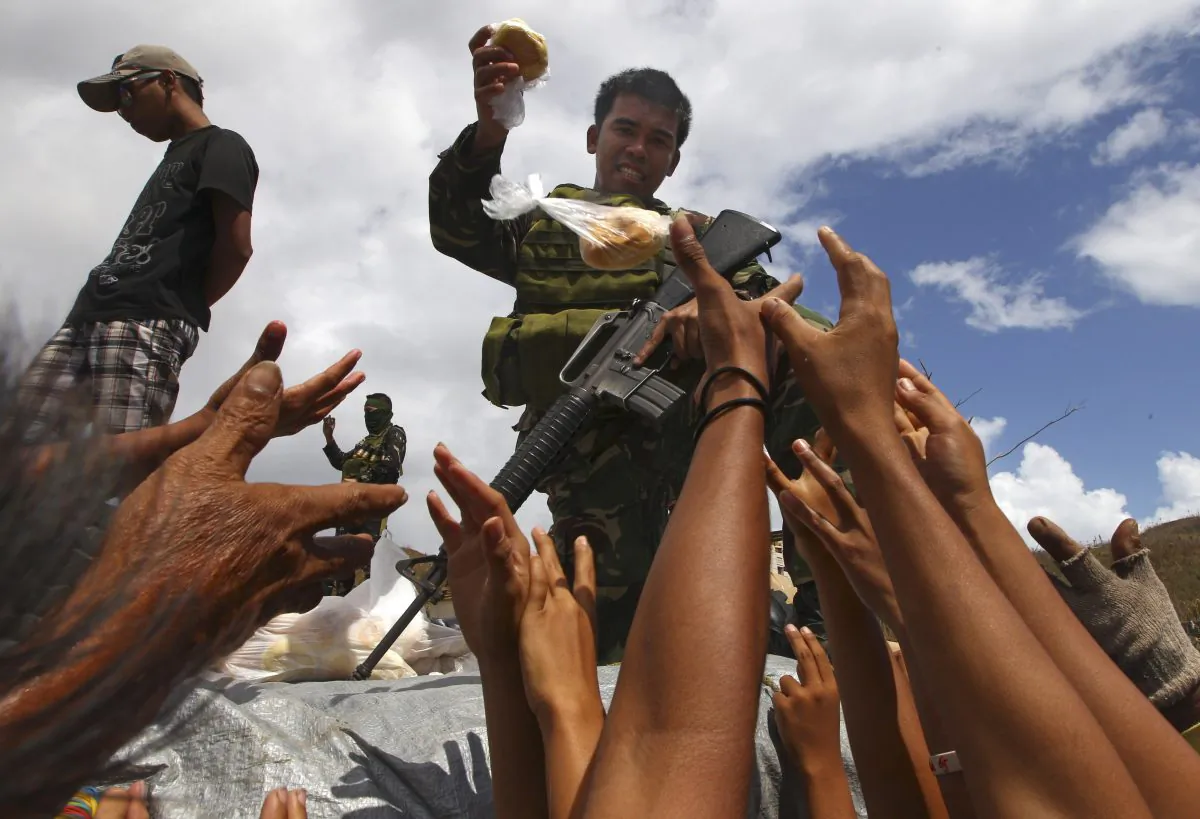 A Filipino soldier hands out bread to the survivors of Typhoon Haiyan in Maraboth, Philippines, Nov. 14, 2013. (Dita Alangkara/AP)