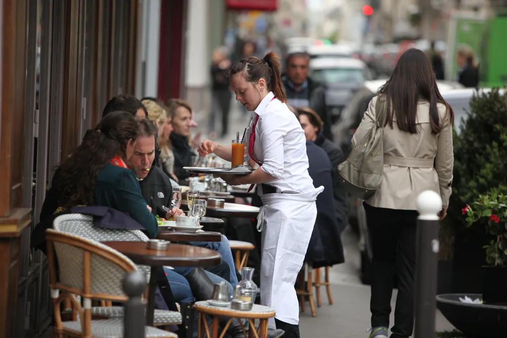 Parisians and tourist enjoy eat and drinks in cafe sidewalk in Paris, France on April 27, 2013. Paris is one of the most populated metropolitan areas in Europe.