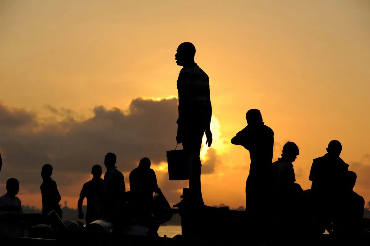 Tanzanian fishermen stand on their boats at sunrise on Sep. 27, 2013, in Dar es Salaam. (Daniel Hayduk/AFP/Getty Images)