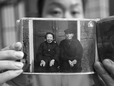 Screenshot showing the couple’s granddaughter holding a picture of the two of them from the 1980s. (Screenshot/Wuhan Evening Times)