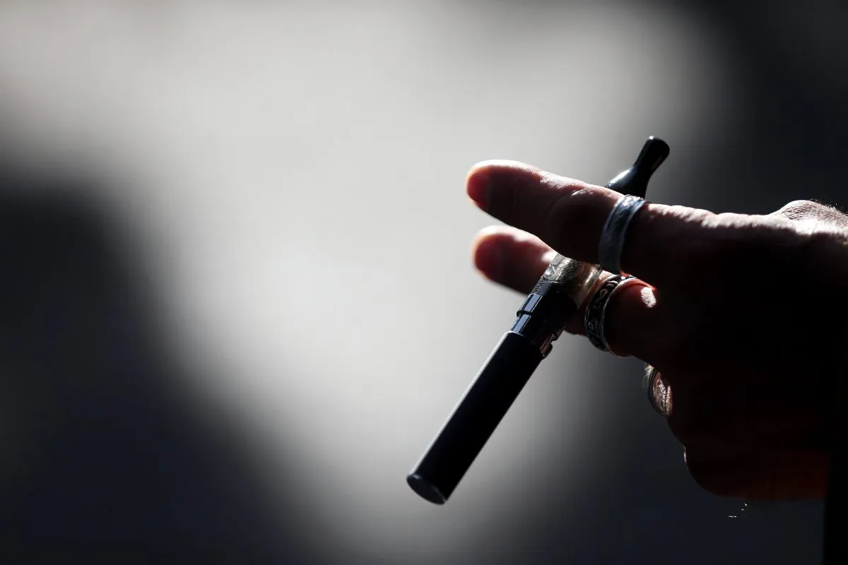A person holds an electronic cigarette on Sept. 12, 2013. The FDA is in the process of extending its authority on tobacco products to include e-cigarettes, but city and state officials want to close the regulation gap now. (Franck Fife/AFP/Getty Images)