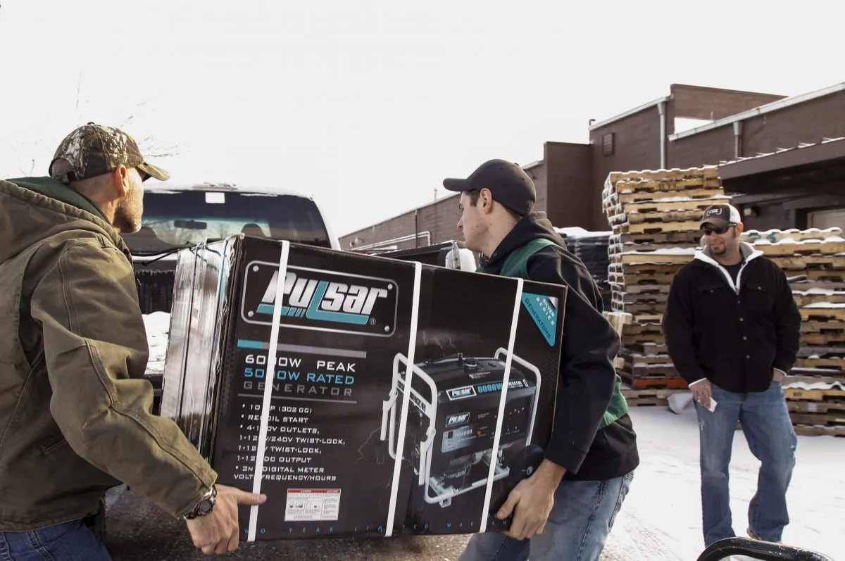 Family Farm & Home of Mason employees  Dean Haynes (L) and Bobby Hollon (C) load a generator into Nathan Timm's (R) truck, Dec. 24, 2013. Timm was buying the generator for his parents, who were without electricity. (Matthew Dae Smith/AP Photo/Lansing State Journal)