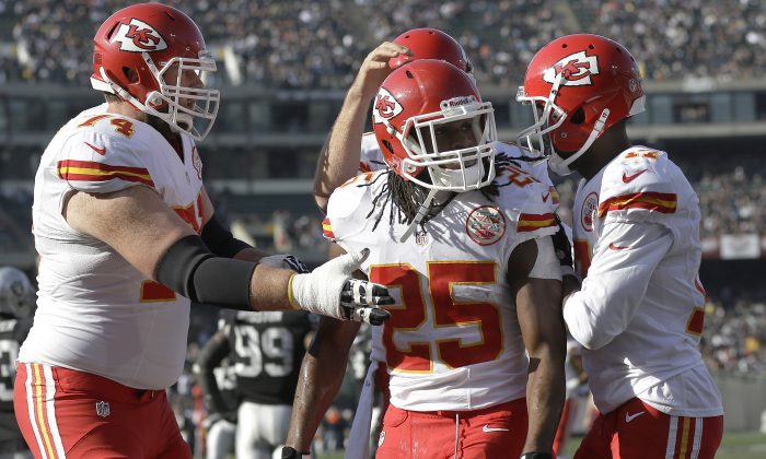 Kansas City Chiefs running back Jamaal Charles (25) celebrates after scoring on a 39-yard touchdown reception with guard Geoff Schwartz, left, quarterback Alex Smith, rear, and wide receiver Donnie Avery against the Oakland Raiders during the first quarter of an NFL football game in Oakland, Calif., Sunday, Dec. 15, 2013. (AP Photo/Marcio Jose Sanchez)