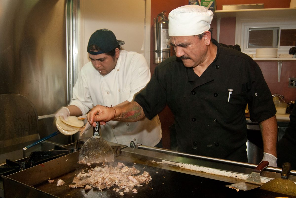 Galdino Molinero (R), also widely known as Tortas, making carnitas tacos. (Joshua Philipp/Epoch Times)
