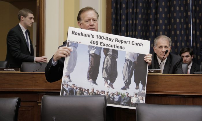Representative Randy Weber (R-TX) carries in a poster accusing Iranian President Hassan Rouhani of hundreds of executions while waiting for Secretary of State John Kerry to arrive to testify before the House Foreign Affairs Committee in Washington, D.C. on Dec. 10, 2013. (T.J. Kirkpatrick/Getty Images)