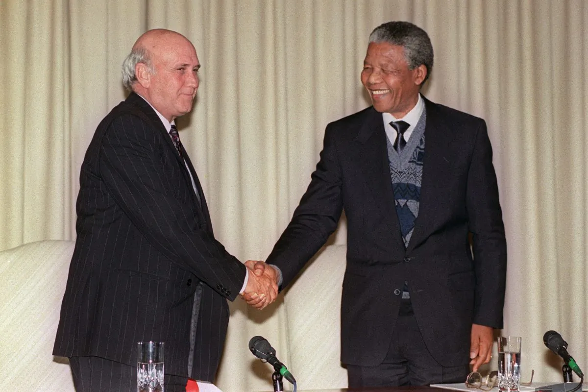 South African president Frederik W. de Klerk (L) and African National Congress (ANC) representative Nelson Mandela (R), smile and shake hands after at a joint press conference, Aug. 7, 1990 in Pretoria, following a marathon meeting between South African governement and ANC, in which ANC agreed to suspend its 29 years of armed struggle. (Alexander Joe/AFP/Getty Images)