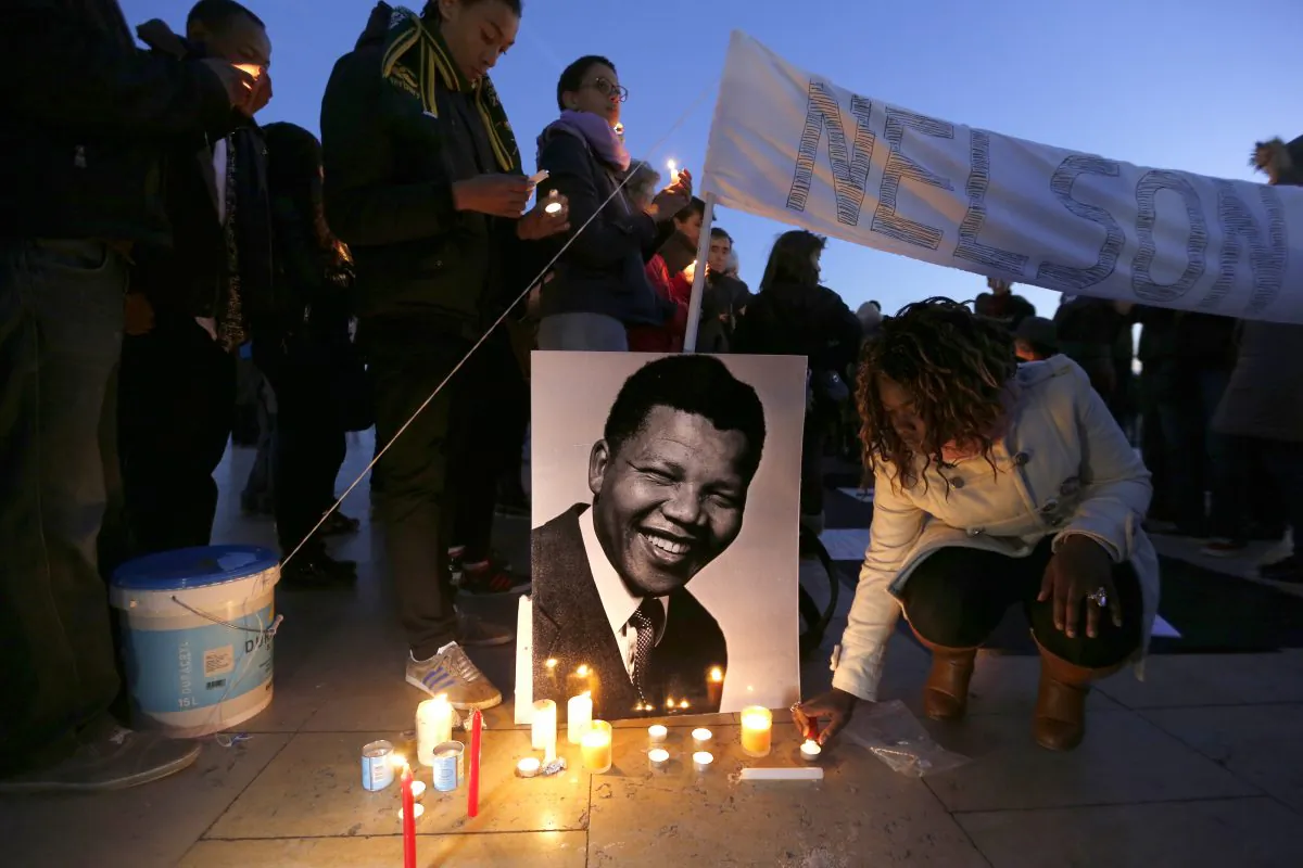 A woman lights a candle next to a portrait of late South African President Nelson Mandela during a tribute to Mandela on the Parvis des droits de l'homme (Human Rights square) in central Paris on Dec. 15, 2013. (Francois Guillot/AFP/Getty Images)