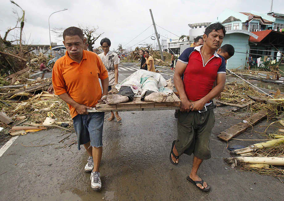 Tacloban City, Philippines -- Haiyan survivors carrying a dead body (Romeo Ranoco/Reuters)