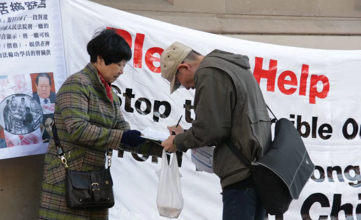 A passerby in Sydney, Australia, signs a petition calling for an end to the atrocity of forced organ harvesting of Falun Gong practitioners in China, on July 6, 2013. The signature is one of nearly 1.5 million from across the world presented to the office of the U.N. High Commissioner for Human Rights on Dec. 9, 2013. (Minghui.org)