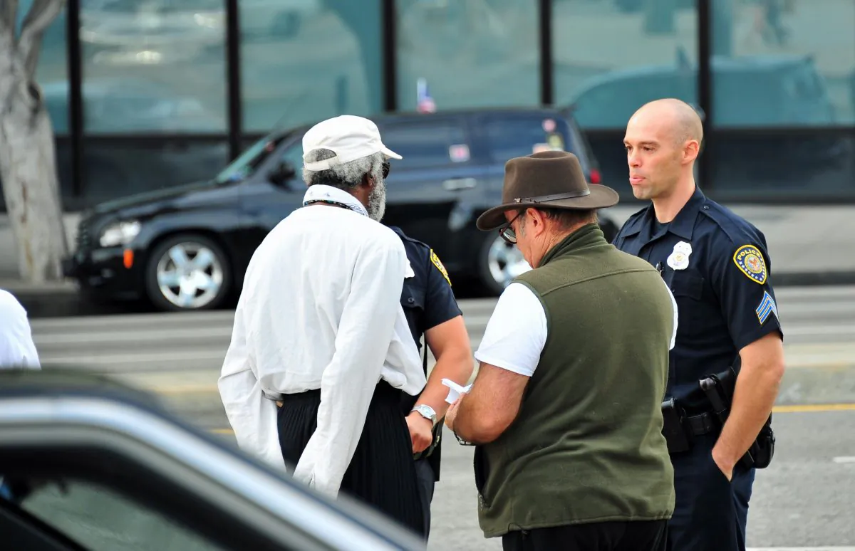 Police demand that placards leaning against the LA Veterans Affairs fence be removed. Veterans were present protesting illegal land use on the VA campus. (Robin Kemker/The Epoch Times)
